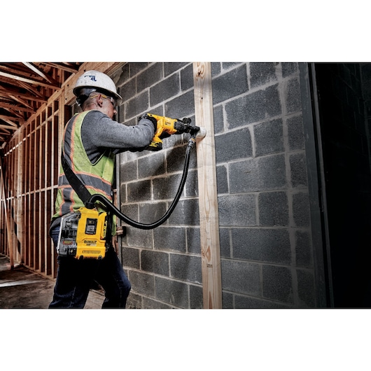 Close up of Brushless universal dust extractor being used by a person to cut out drywall.
