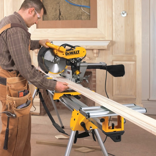 12 inch double bevel sliding compound miter saw being used to saw a wooden plank by a worker.