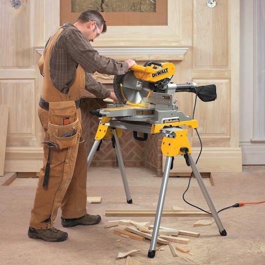 12 inch double bevel sliding compound miter saw being used to cut wood by a worker at a worksite.