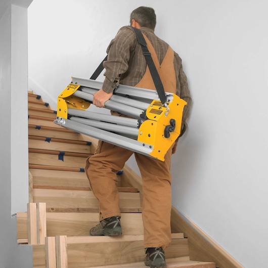 12 inch double bevel sliding compound miter saw being carried up stairs by a worker.