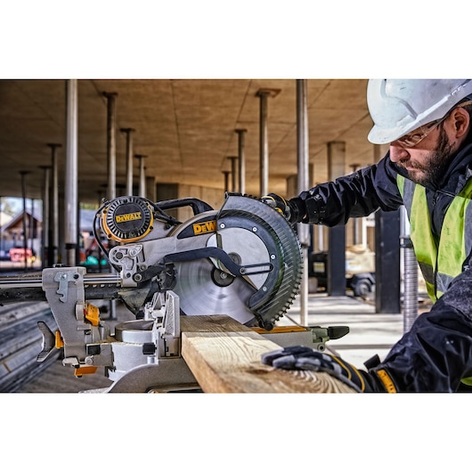 12 inch double bevel sliding compound miter saw being used to cut pieces of wall panels by a worker.