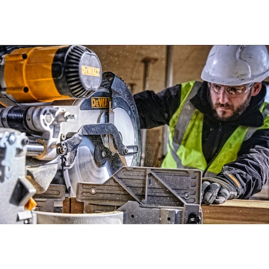 12 inch double bevel sliding compound miter saw cutting a wooden panel.