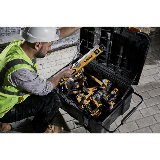 Construction worker pulling a box beam level from an open TSTAK job chest