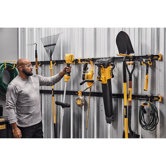 A Person Grabbing an Outdoor Tool off of a DEWALT Metal Rail Featuring Lawn/Garden Kits