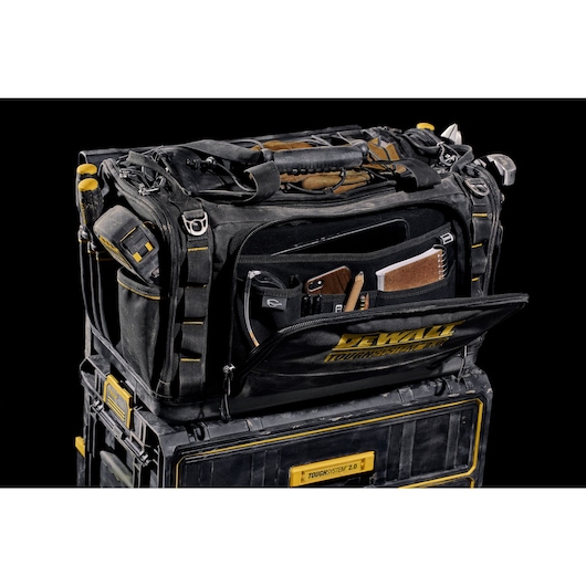 Front view of open DEWALT TOUGHSYSTEM 2.0 22-inch jobsite soft storage toolbag holding DEWALT screwdrivers and other hand tools and open front pocket hold notebook, phone and pencils.