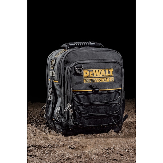 Front view of closed DEWALT TOUGHSYSTEM 2.0 11-inch compact soft storage toolbag sitting on wet dirt.