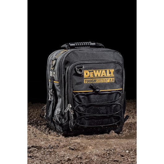 Front view of closed DEWALT TOUGHSYSTEM 2.0 11-inch compact soft storage toolbag sitting on wet dirt.